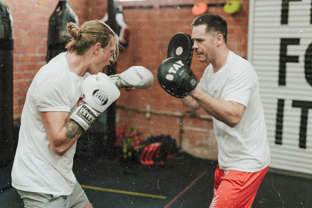 Twee kickboksers met handschoenen in een gym.